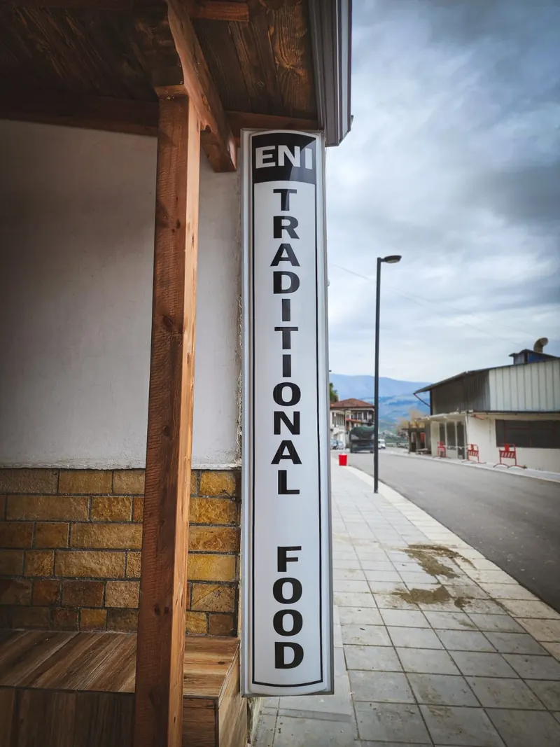The vertical Eni Traditional Food sign at the entrance, by the street