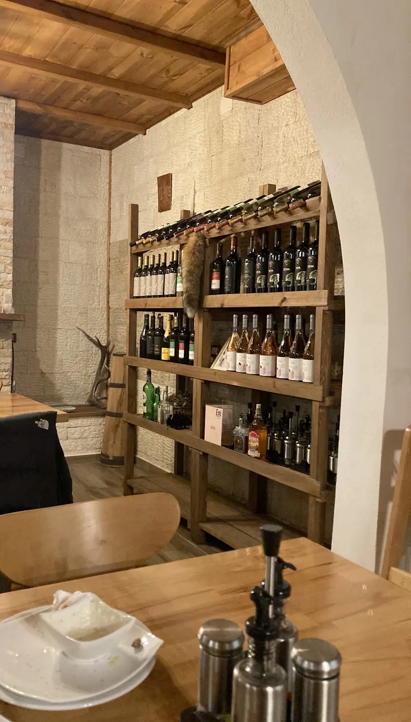 Wooden shelves of wine bottles beside a white arch